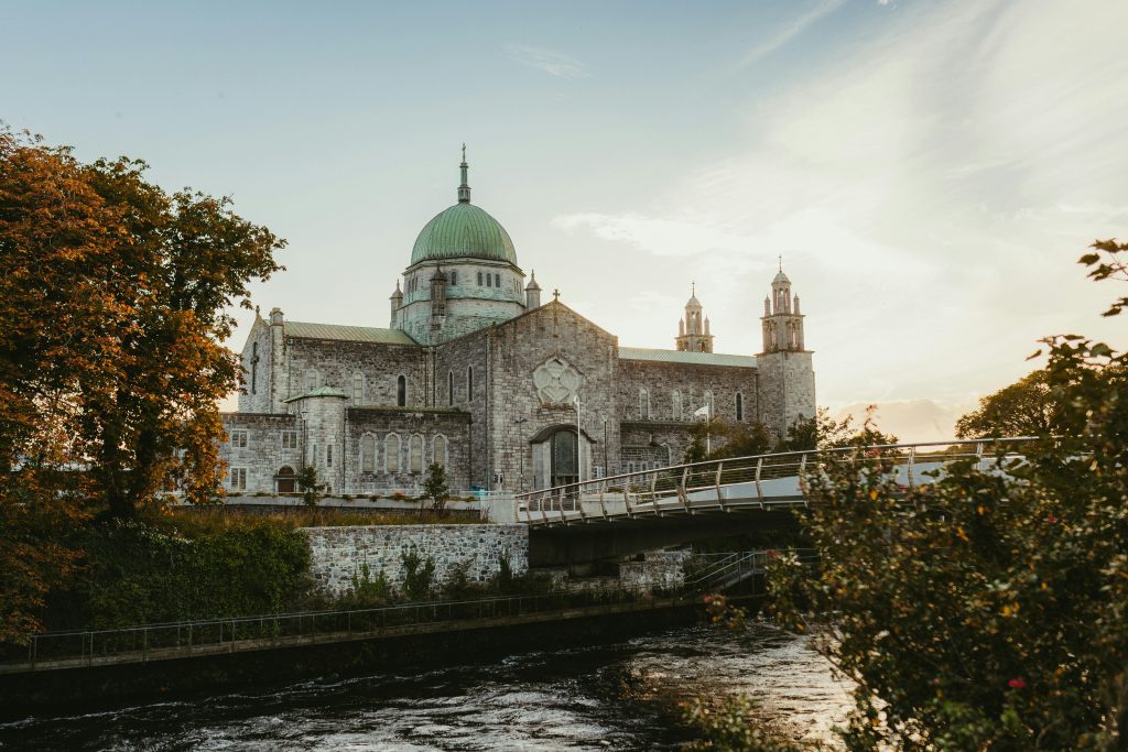 Stunning view of St. Nicholas' Cathedral in Galway, Ireland, captured at dusk with a serene river foreground.